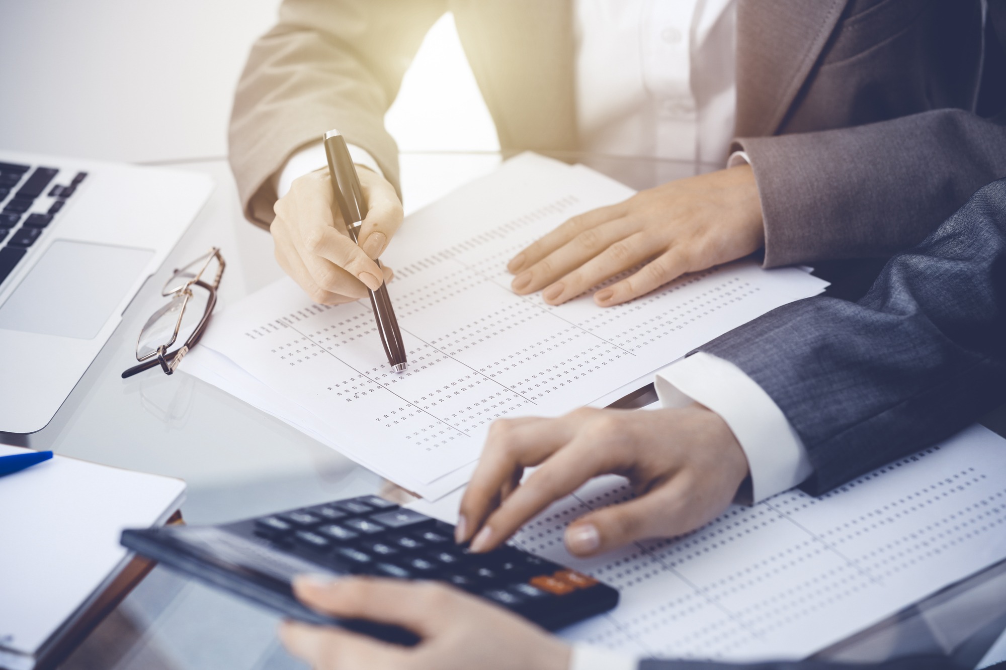 Two Female Accountants Counting On Calculator Income